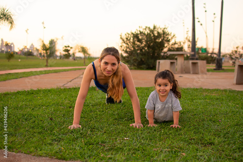 madre e hija haciendo flexiones de brazos en un parque al aire libre  photo