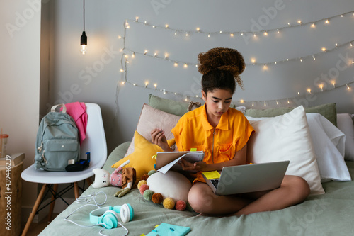 Schoolgirl learning online on bed photo