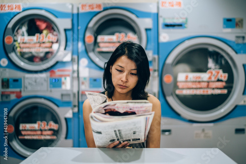 Young Asian woman waiting in a laundromat photo