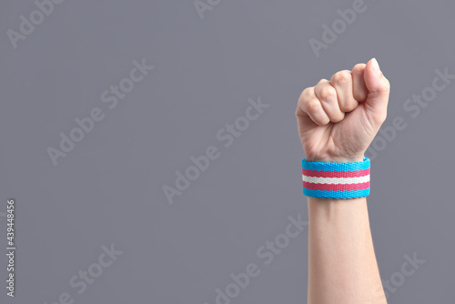 Papier peint Raised fist of a young person wearing a transgender flag bracelet; trans pride