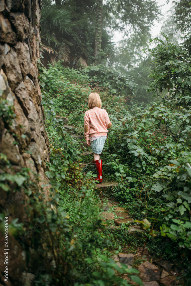 Little girl walking along a green wooded trail Little girl walking along a green wooded trail
