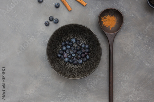 Backgrounf: black table with a bowl with blueberry and a spoon with cinnamon photo