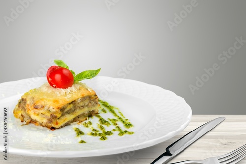 Tasty hot lasagna dish with tomato sauce and cheese served with tomatoes on a plate