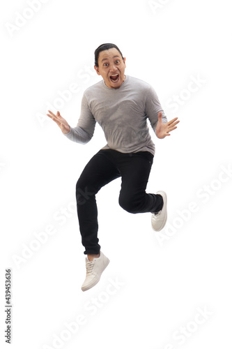 Asian man wearing grey shirt black denim and white shoes, jump while screaming shouting celebrating victory, winning gesture