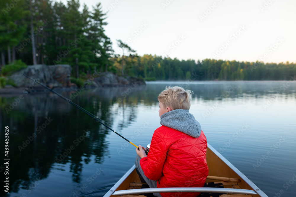 Boy in canoe fishing early morning Muskoka lake Boy in canoe fishing early morning Muskoka lake