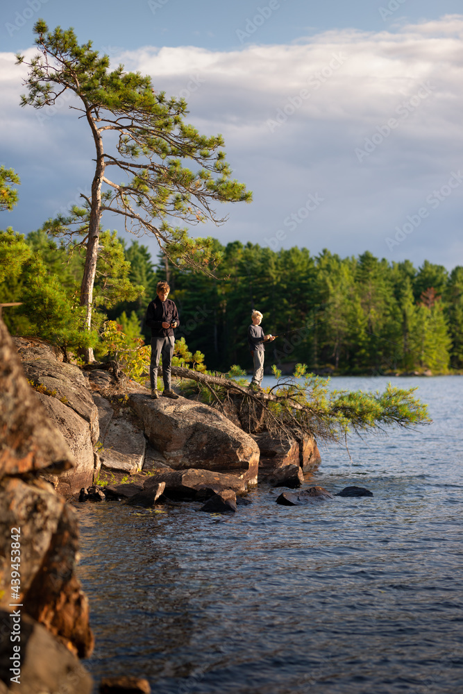 Boys in Muskoka wilderness fishing trip cast lines into lake Boys in Muskoka wilderness fishing trip cast lines into lake