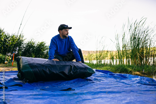 Fisherman preparing boat near pond 