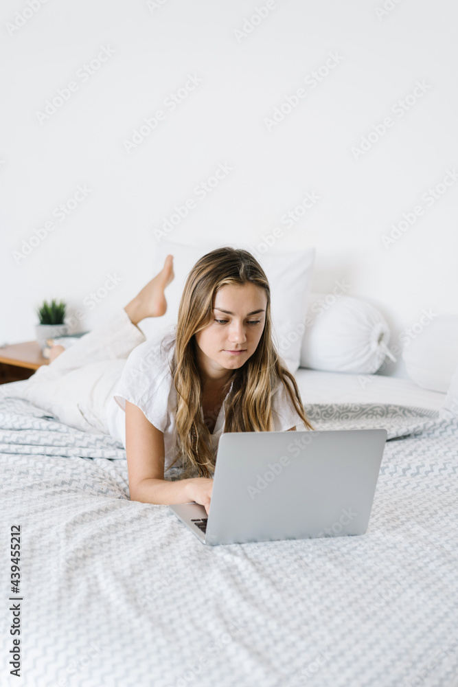 Serious woman working on laptop in bedroom Serious woman working on laptop in bedroom