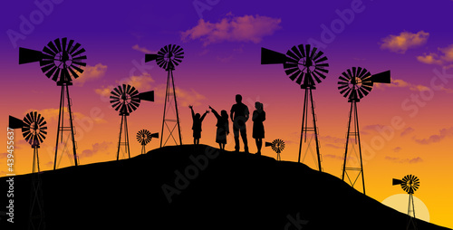 A family looks at a display of vintage water pumping windmills at sunset in this illustration about agriculture.