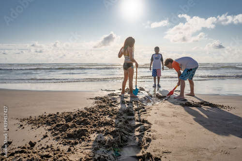 Three Children dig a trench at beach