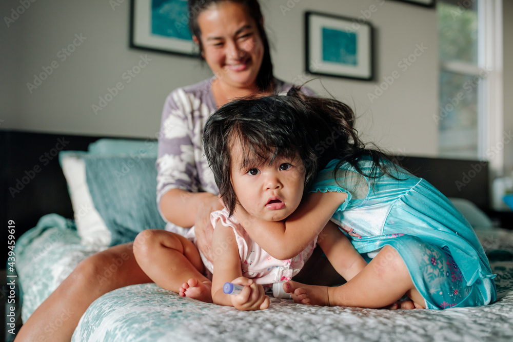 Smiling mom bed watching daughters hug Smiling mom bed watching daughters hug