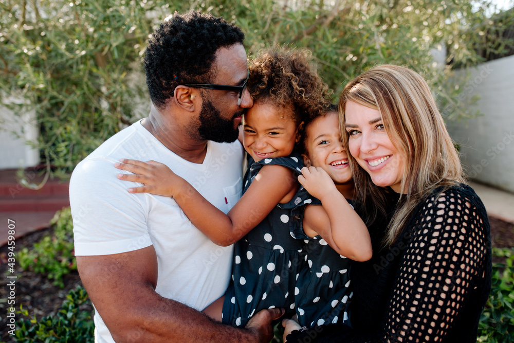 Smiling happy parents holding joyful biracial daughters Smiling happy parents holding joyful biracial daughters