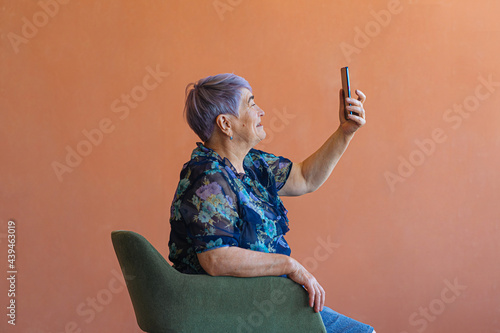 Senior woman taking selfie in armchair