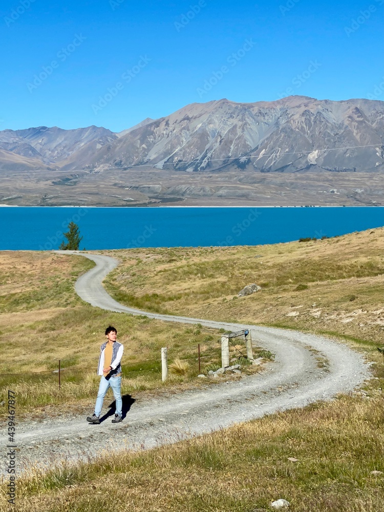 Person carrying tripod walking along road in New Zealand. Travel New Zealand. Places to go in New Zealand.