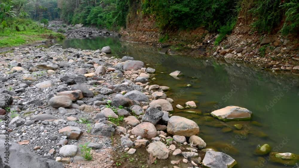 Beautiful riverside landscape view with volcanic rocks boulder and green clear water Beautiful riverside landscape view with volcanic rocks boulder and green clear water