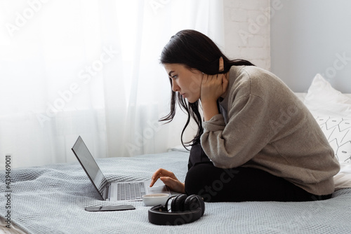Young woman using laptop on bed