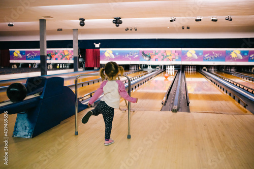 little girl bowls at bowling alley