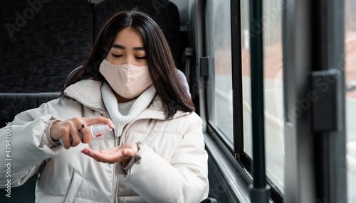 Asian woman disinfecting hands in bus photo