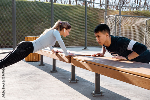 Young sportsman and sportswoman doing push ups on bench