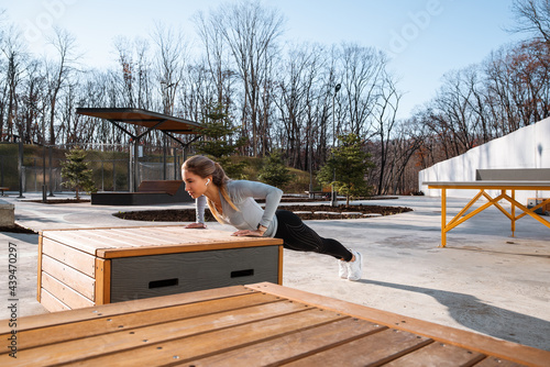 Young sportswoman doing push ups on bench