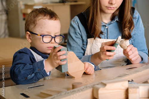 Mother and kid working in carpentry workshop photo