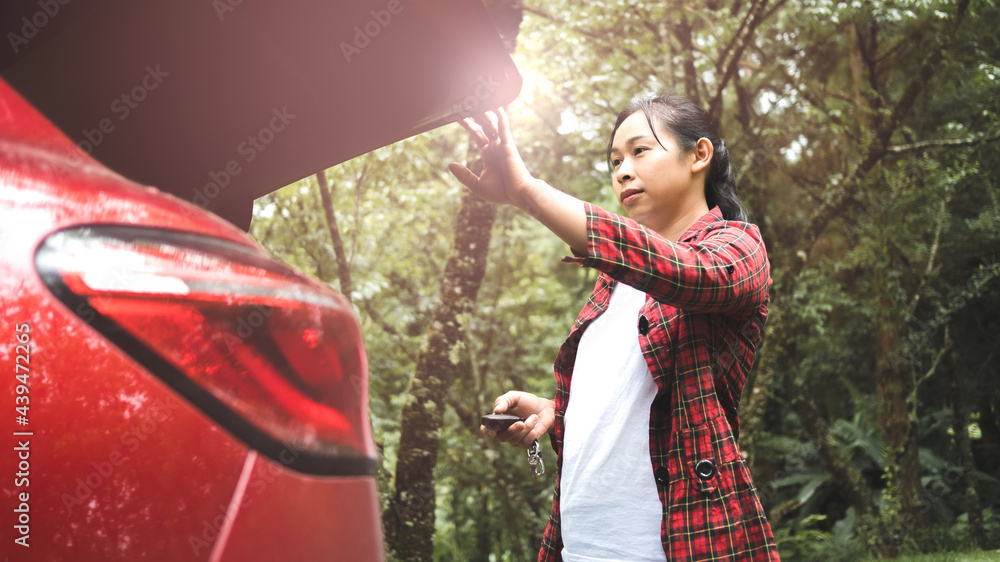 A young woman pressing the button to close the trunk of the car