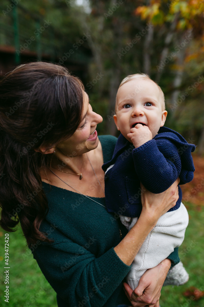 Loving mom holding and cuddling cute baby boy outside in the wal Loving mom holding and cuddling cute baby boy outside in the wal
