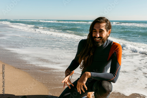 long hair man in neoprene suit at the beach coast
