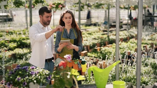 Wallpaper Mural A young handsome man in a greenhouse talks to a female gardener with a tablet Torontodigital.ca