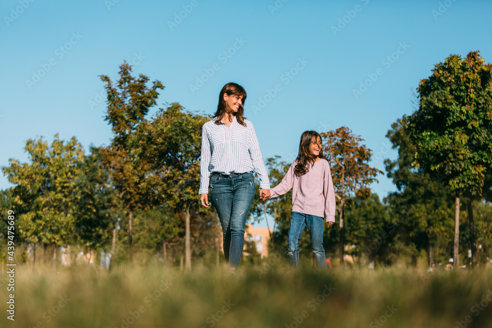 Delighted woman and girl walking in park Delighted woman and girl walking in park