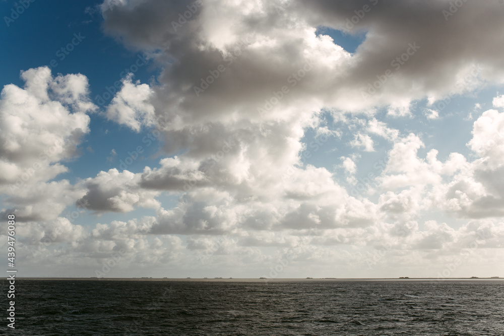White clouds against blue sky over rippling sea
White clouds against blue sky over rippling sea