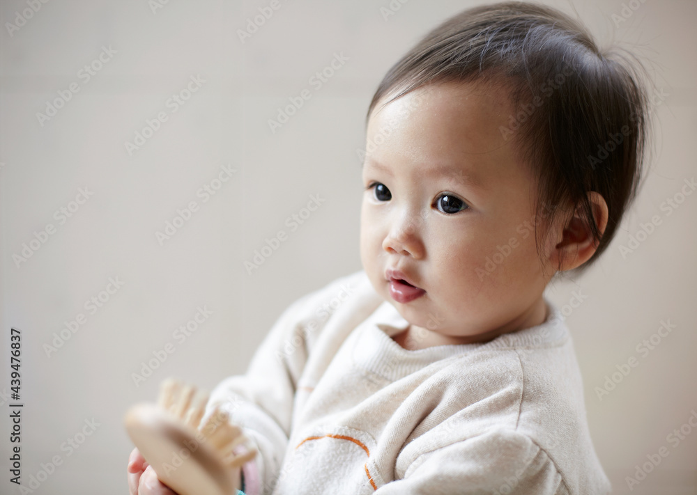 Cute Asian kid playing with comb at home Cute Asian kid playing with comb at home