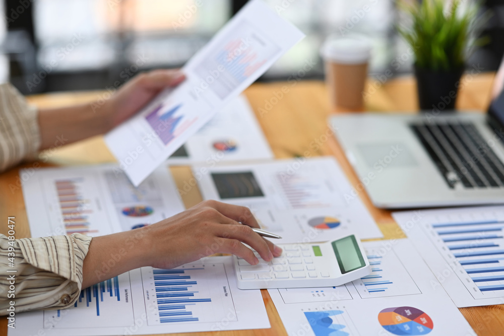 Fotografie Accountant analyzing financial graph and using calculator at office