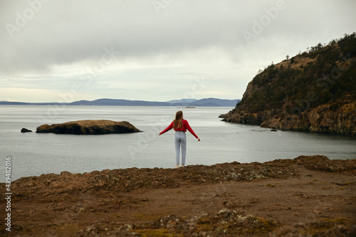 Woman in Red standing on coastline photo