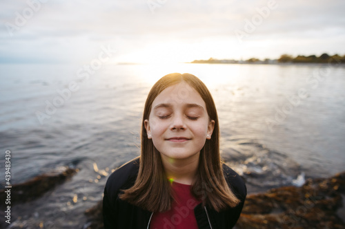 Young girl on beach with eyes closed in expectation