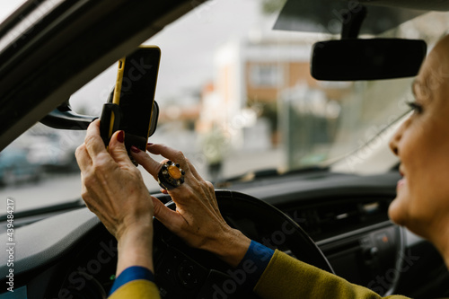 Close-up of senior woman placing her phone on the gps holder at car 
