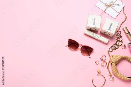 Stylish female accessories with calendar on color background