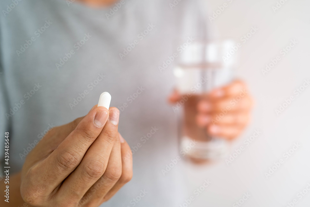 Close up of a man holding a dietary supplement or medication and a glass of water ready to take medicine. health concepts of people. Close up of a man holding a dietary supplement or medication and a glass of water ready to take medicine. health concepts of people.
