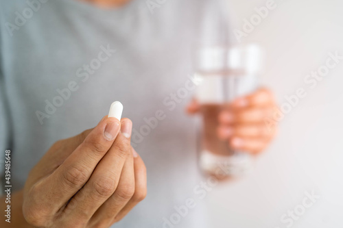 Close up of a man holding a dietary supplement or medication and a glass of water ready to take medicine. health concepts of people.