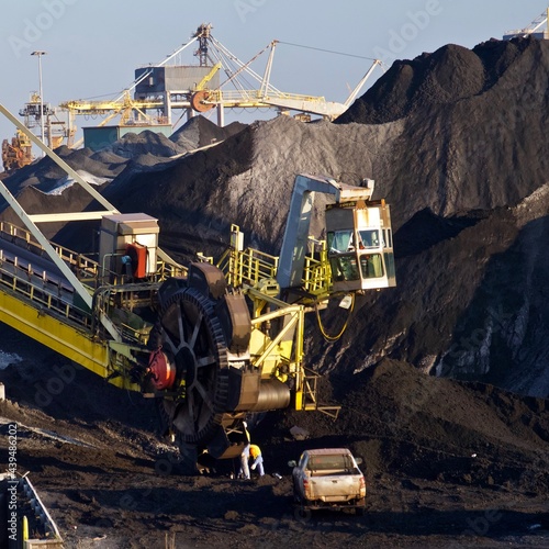 Men repairing massive coal mining machinery to dig up fossil fuels for carbon economy photo