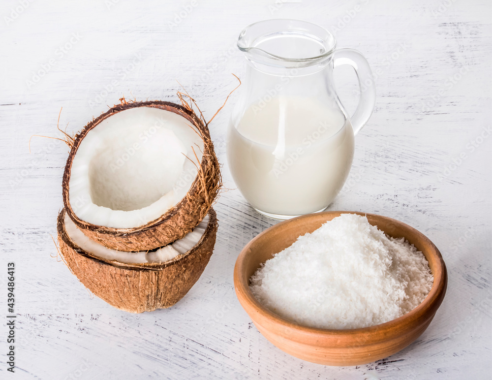 coconut milk with coconut chips and broken coconut on a white textured background coconut milk with coconut chips and broken coconut on a white textured background