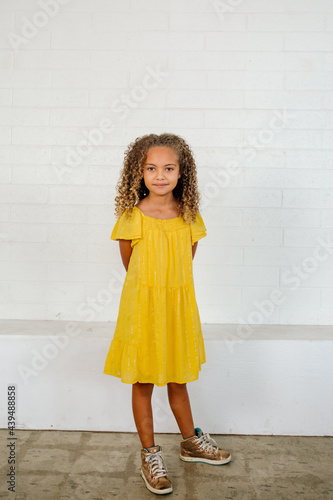 Beautiful young bi-racial girl wearing vivid yellow dress and high top sneakers