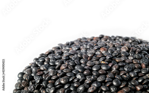 Beluga lentils pile, close up. Many tiny black organic lentils. Legume with earthy flavor, firm texture and high in protein. Used as side dish, in soups and salads. Selective focus. Isolated on white.