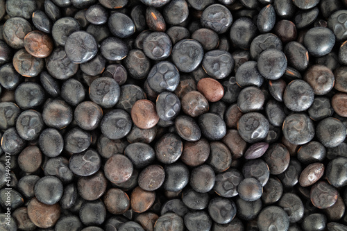 Beluga lentils  close up. Top view of many tiny black organic lentils. Legume with earthy flavor  firm texture and high in protein. Used as side dish  in soups and salads. Selective focus.