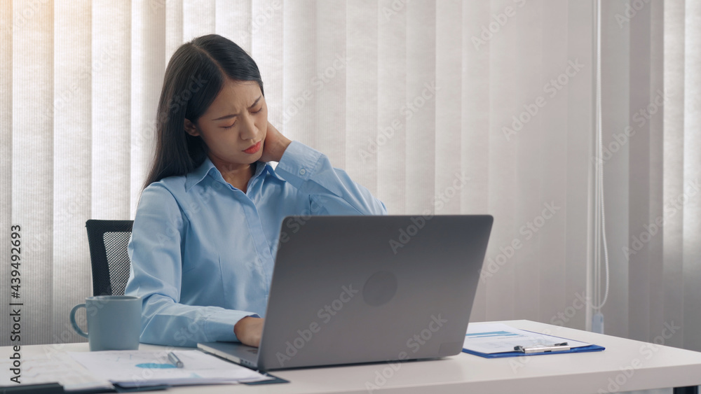 Young asian woman is sitting in a corporate office and has pain in her neck. Young asian woman is sitting in a corporate office and has pain in her neck.