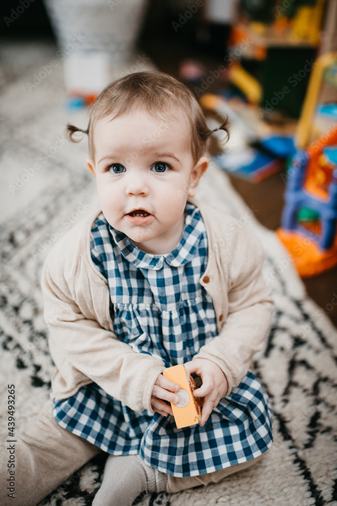 Baby girl sitting on the carpet and playing with toys Baby girl sitting on the carpet and playing with toys