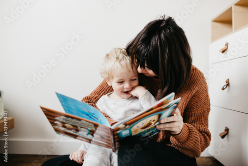 Mother and child reading a book in toddlers bedroom photo