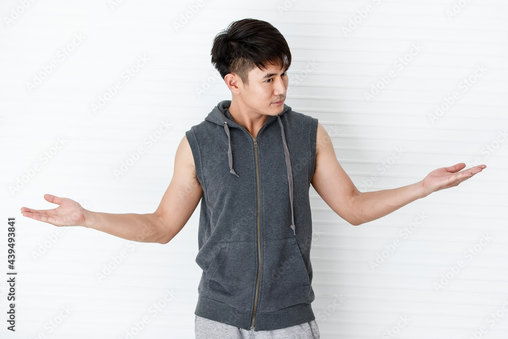 Asian handsome fit smiling man looking unhappy and angry showing rejection hands sign, wearing sleeveless t-shirt gray sportswear in white background. Asian handsome fit smiling man looking unhappy and angry showing rejection hands sign, wearing sleeveless t-shirt gray sportswear in white background.