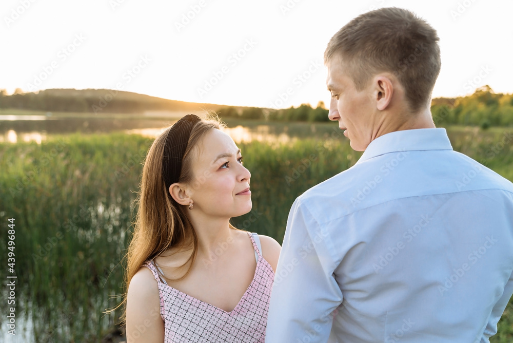 a young couple in love, a guy and a girl on an outdoor date on a lake at sunset in a nature park. the concept of romantic relationships, love a young couple in love, a guy and a girl on an outdoor date on a lake at sunset in a nature park. the concept of romantic relationships, love