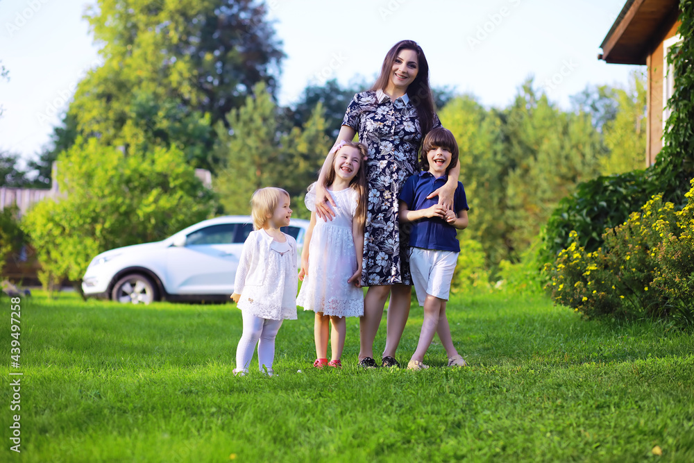 Obraz premium Young large family on a summer morning walk. Beautiful mother with children is playing in the park.